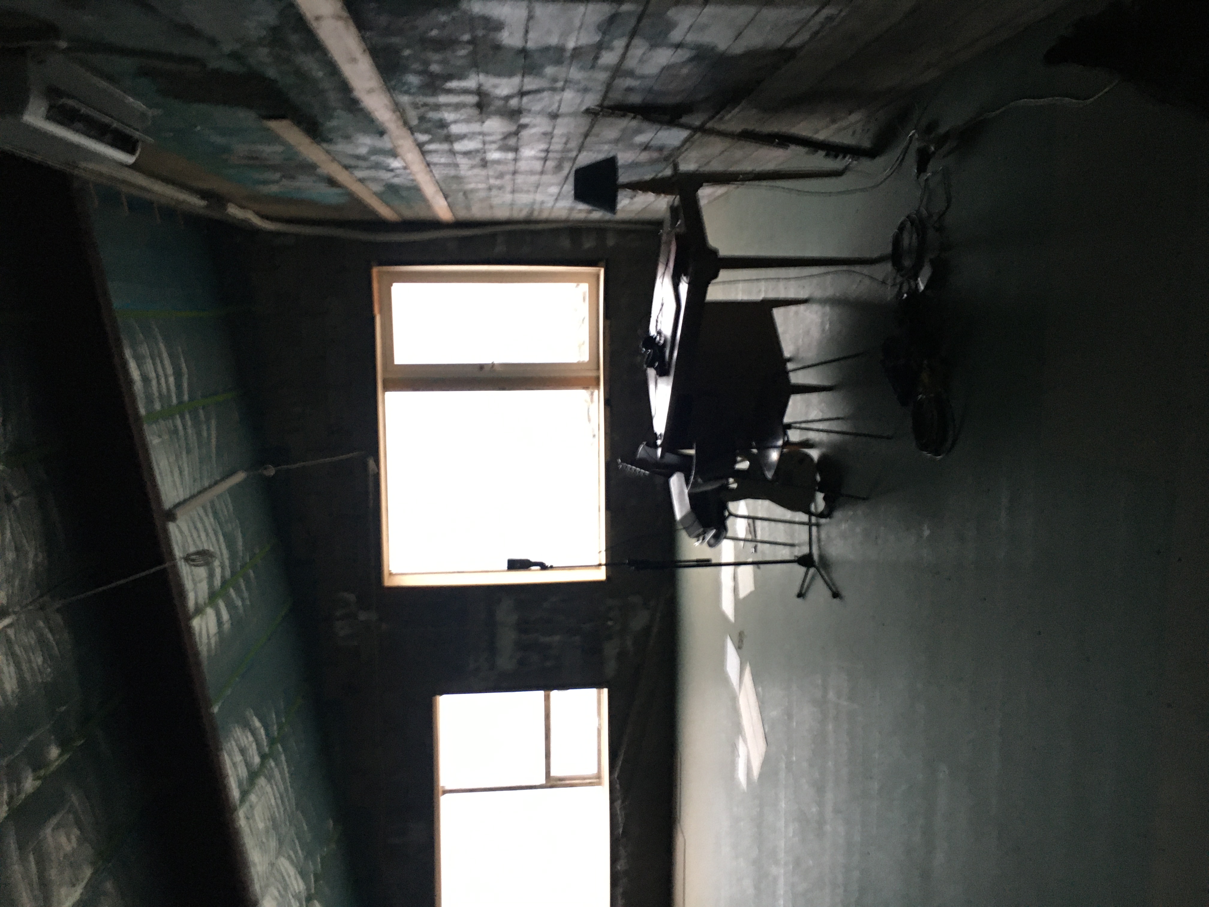 A darkened photograph of Kathryn Mohr's workspace with a simple table and chair plus papers scattered on the floor